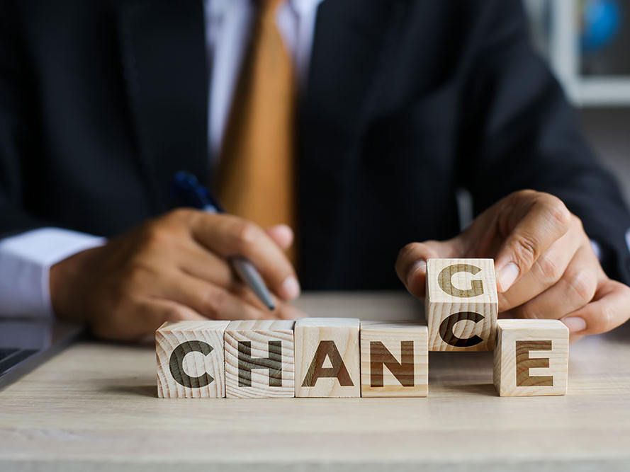 man in a suit holding toy letter blocks that spells change - chance